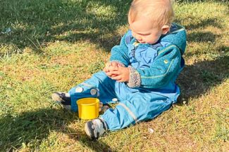 Kleinkind sitzt spielend im Gras